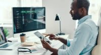 Concentrated young African man in shirt using digital tablet while working in the office